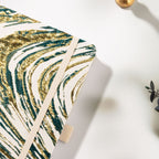 Close-up of the woven dark green fabric cover with shimmering gold marble lines and elastic strap