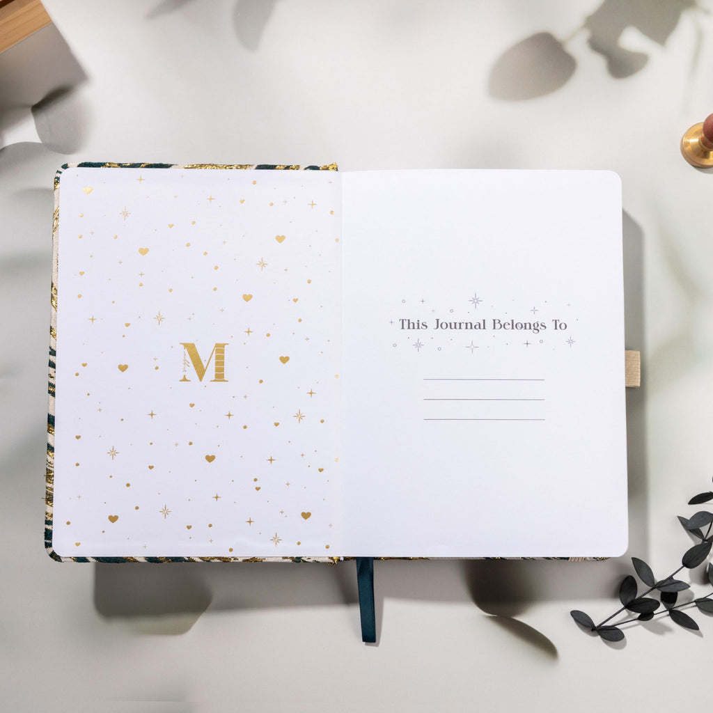 Inside title page featuring a gold foil 'M' logo and 'This Journal Belongs To' section on a green journal