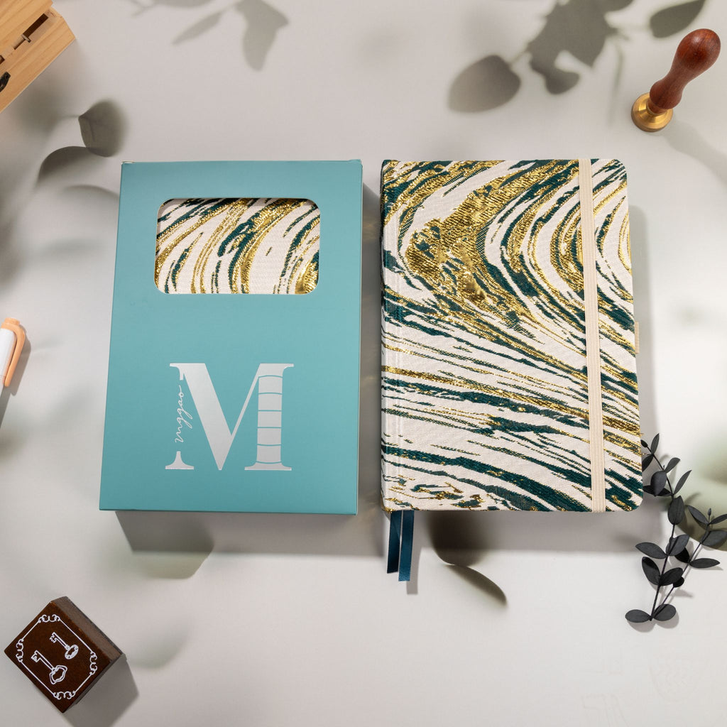 Dark green gold marble fabric notebook displayed next to its signature light blue window-cut gift box