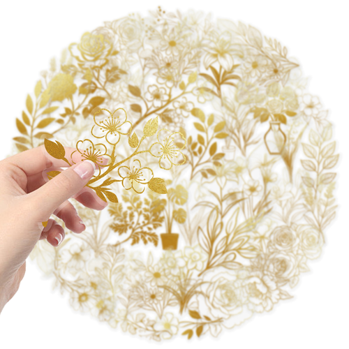 A hand holding a gold foil cherry blossom PET sticker with transparent borders, showing the delicate gold floral design and clear backing.