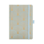 A5 woven fabric notebook with a scalloped embroidery pattern in light green and gold, standing upright on a white background with a matching light blue elastic band.