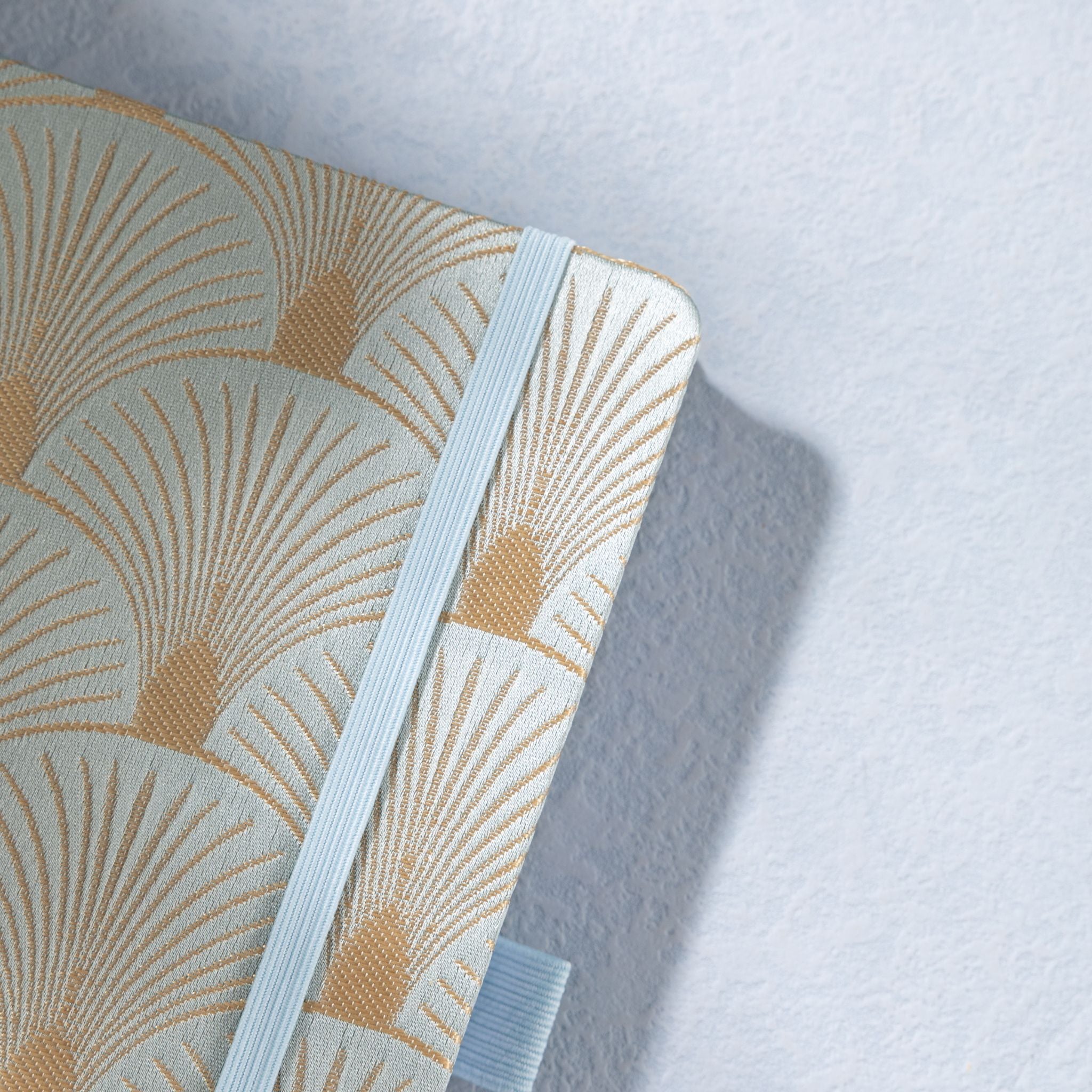 Close-up of the woven green fabric cover with radiating gold scalloped lines and elastic strap