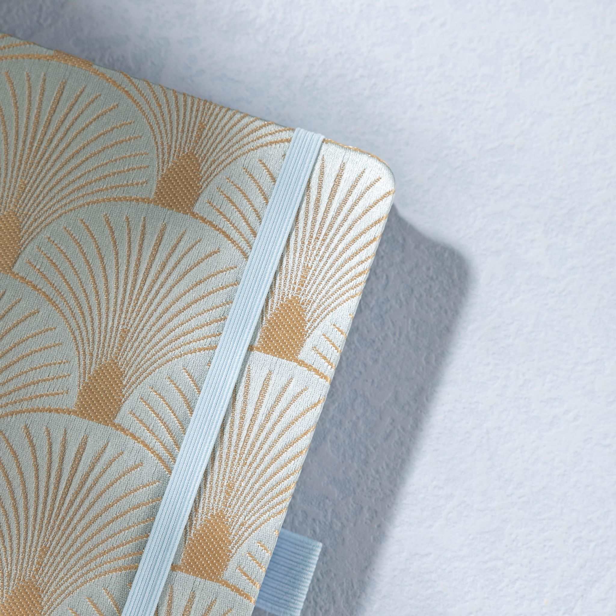 Close-up of the woven green fabric cover with radiating gold scalloped lines and elastic strap