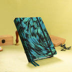 A5 black and green embroidered fabric notebook standing upright on a yellow desk with a sealing wax stamp