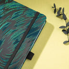 Close-up of the raised green embroidered texture on a black woven fabric cover, with elastic strap