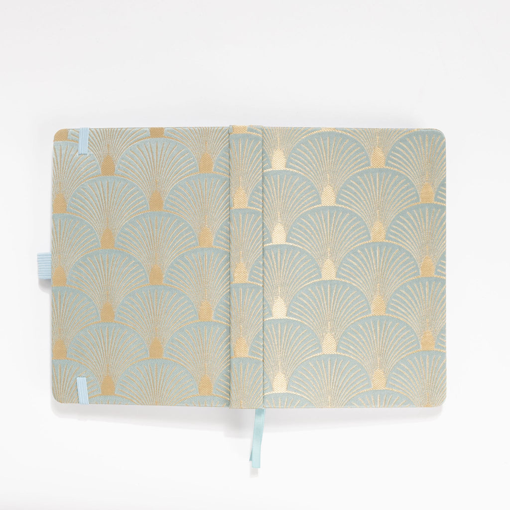 Flat lay of the green and gold scalloped woven fabric cover opened completely.