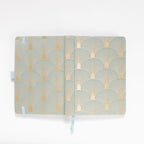 Flat lay of the green and gold scalloped woven fabric cover opened completely.