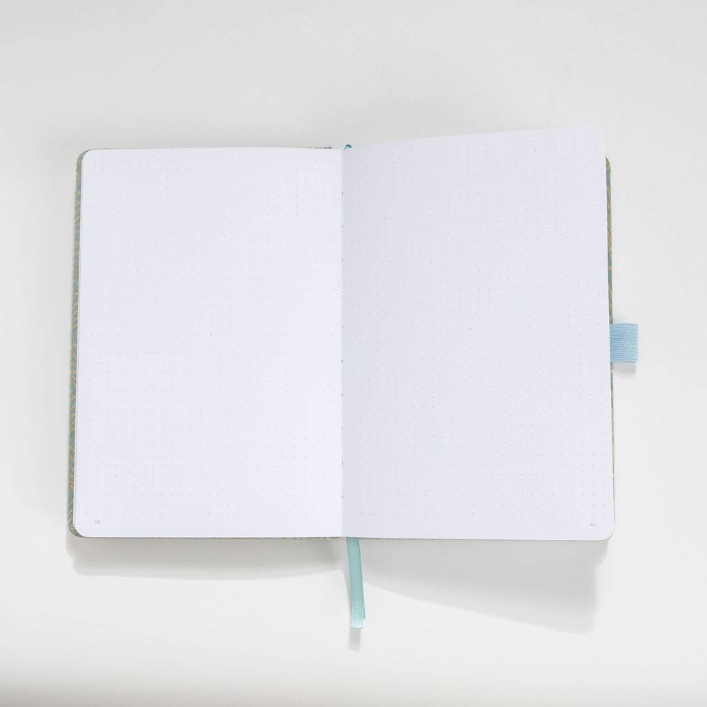Open A5 journal showing the thick 160gsm dot grid interior pages and light blue ribbon bookmark