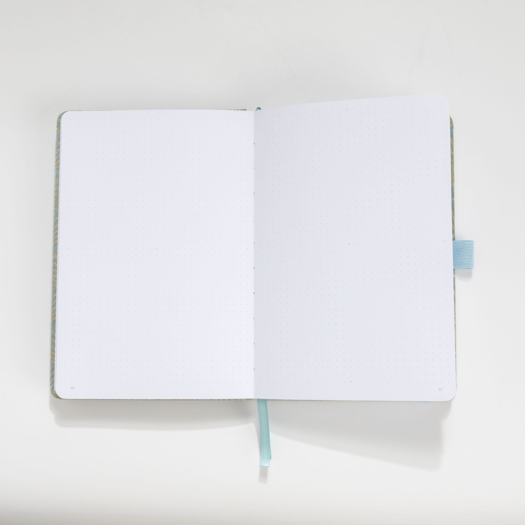 Open A5 journal showing the thick 160gsm dot grid interior pages and light blue ribbon bookmark