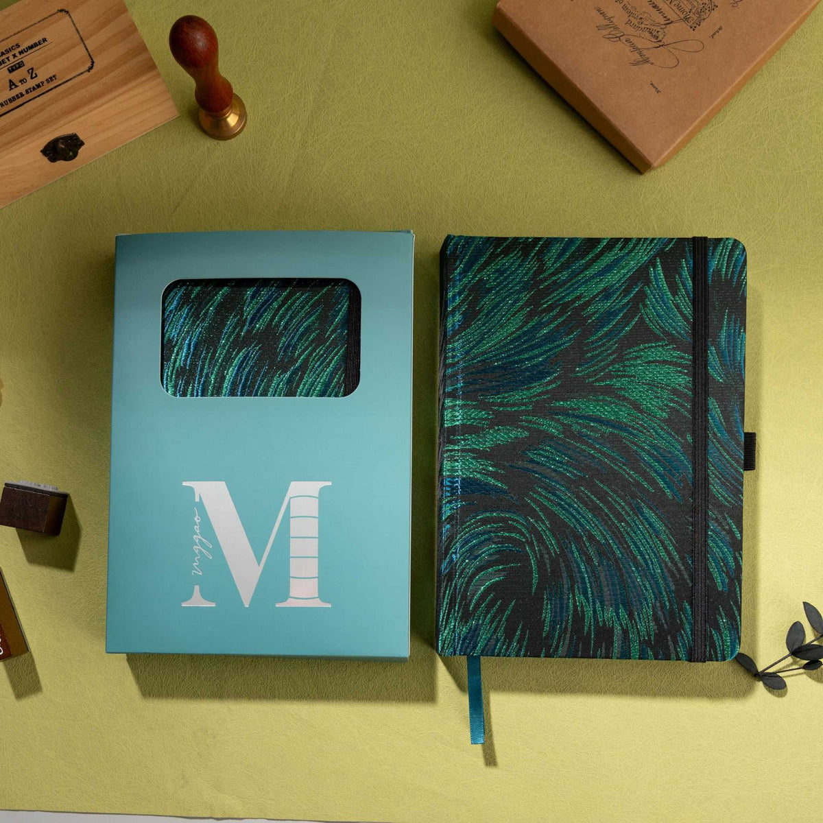 Black and green embroidered fabric notebook displayed next to its signature light blue window-cut gift box.