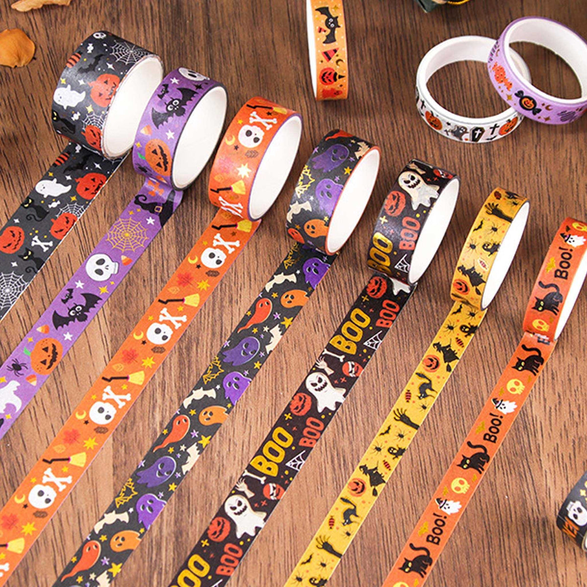 Halloween Gold Foil Washi Tape Set 12 Rolls, Assorted Rolls Fanned Out on Wooden Desk Showing Mixed Widths and Spooky Patterns