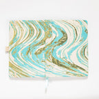 Flat lay of the light blue and gold marble fabric cover opened completely, showing the inner lining and ribbon bookmark