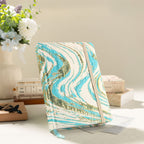Styled desktop shot of the light blue and gold marble cloth notebook standing upright, accompanied by white flowers and a wooden calendar block in warm sunlight.