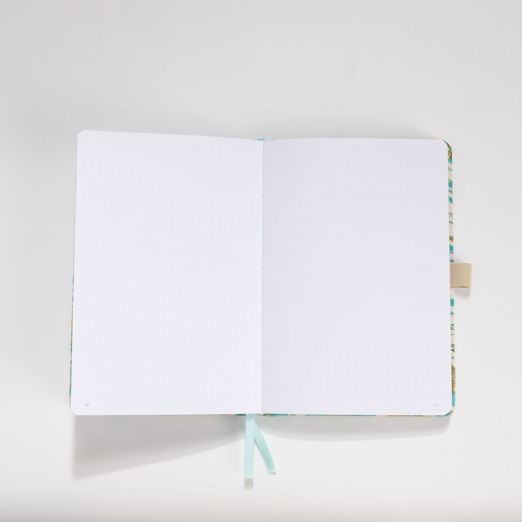 Open A5 journal showing the 160gsm dot grid interior pages with light blue ribbon bookmark