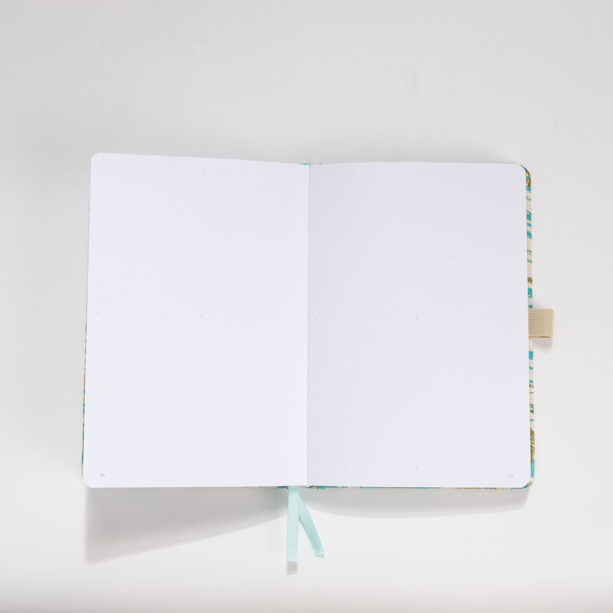Open A5 journal showing the 160gsm dot grid interior pages with light blue ribbon bookmark