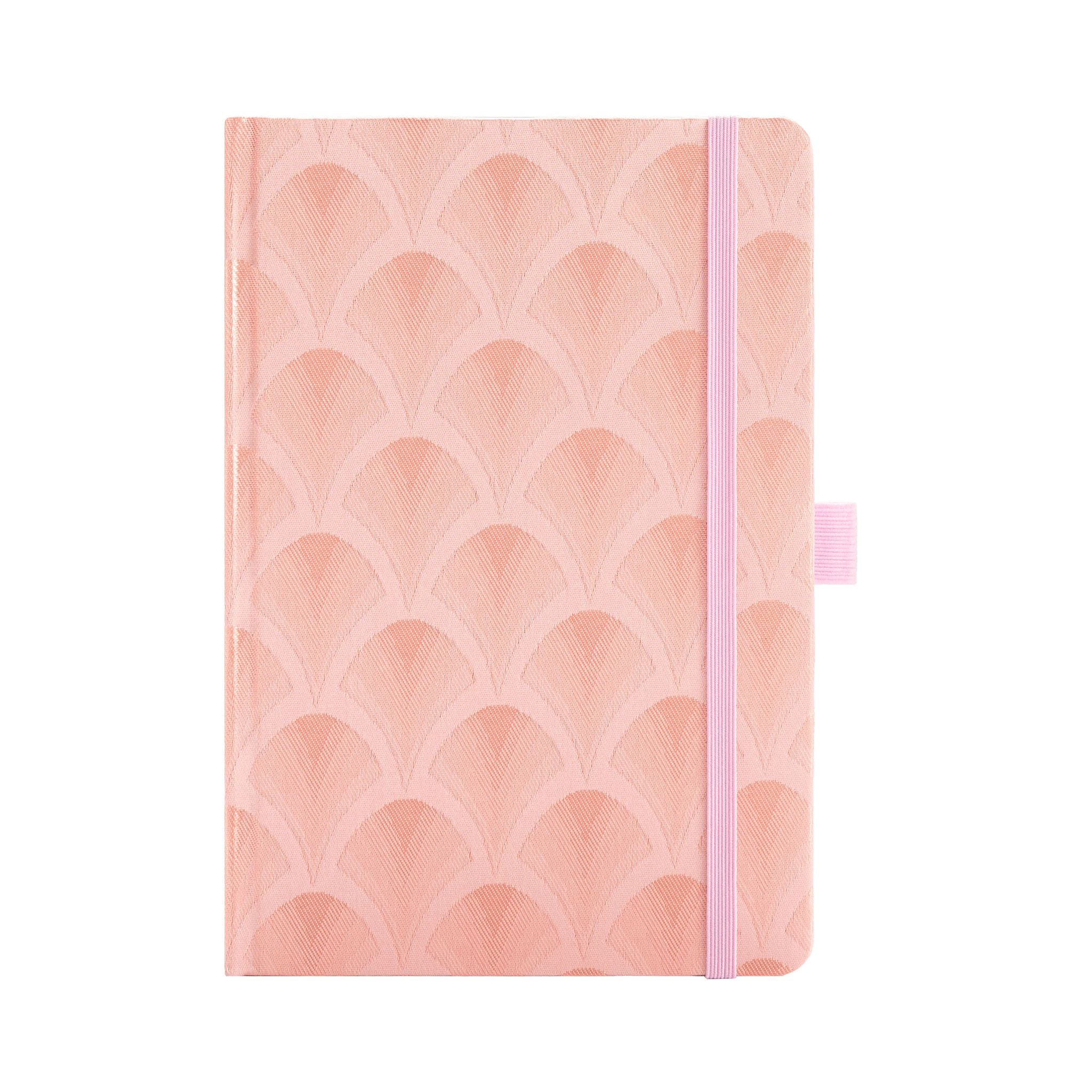 A5 pink woven fabric notebook with a scalloped embroidery pattern, standing upright on a white background with a matching pink 