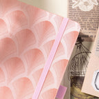 Detail shot of raised scalloped texture and elastic band on pink notebook