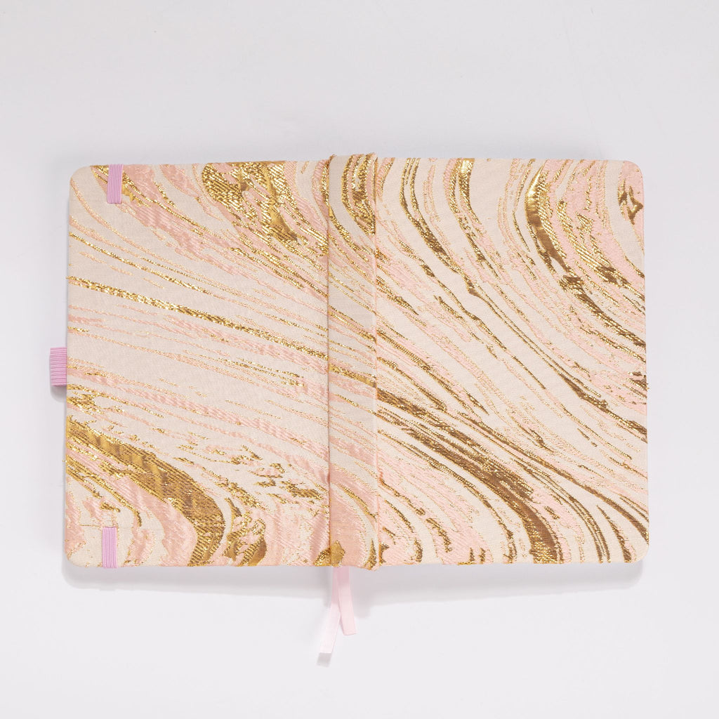 Flat lay of the blush pink and gold marble woven fabric cover opened completely