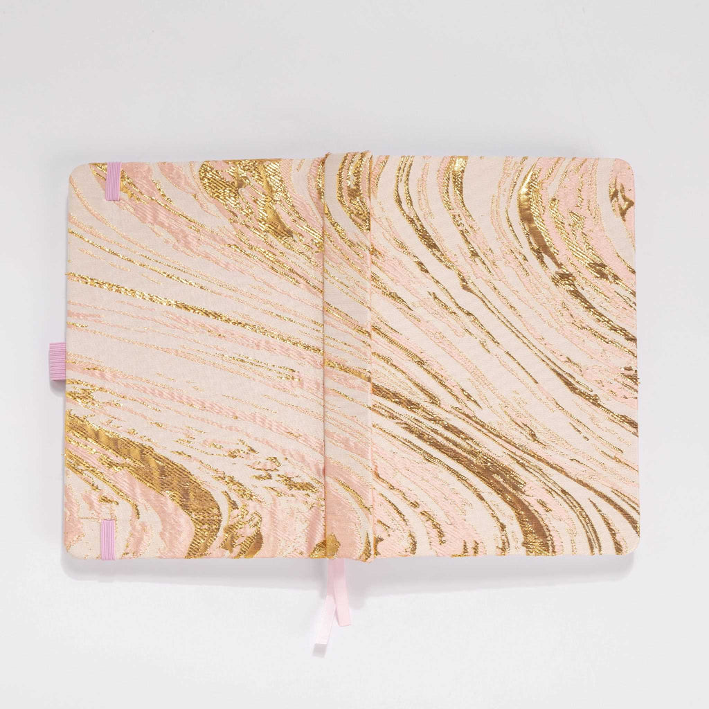 Flat lay of the blush pink and gold marble woven fabric cover opened completely