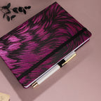 Deep purple and black metallic swirl fabric notebook with black elastic band, holding a white and gold pen