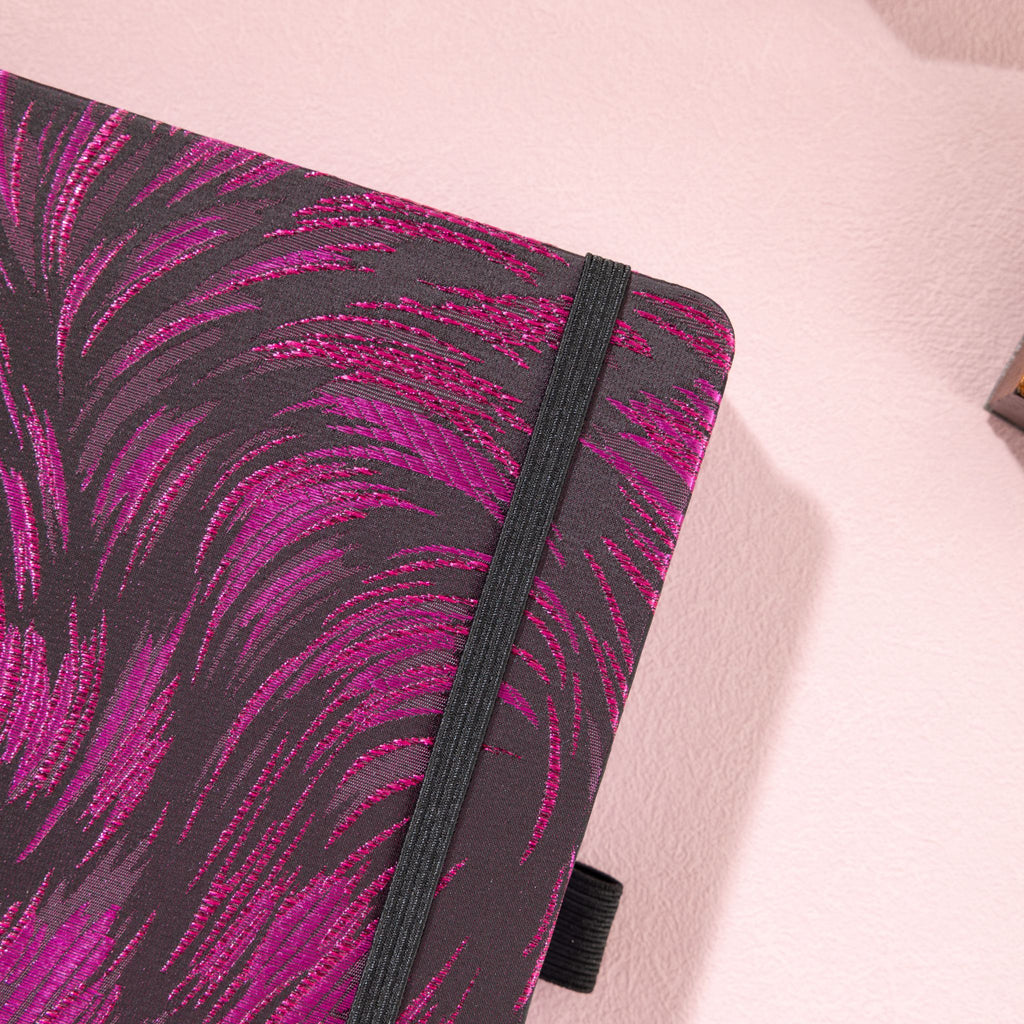 Close-up of the dark purple and black metallic woven fabric cover and matching black elastic strap.