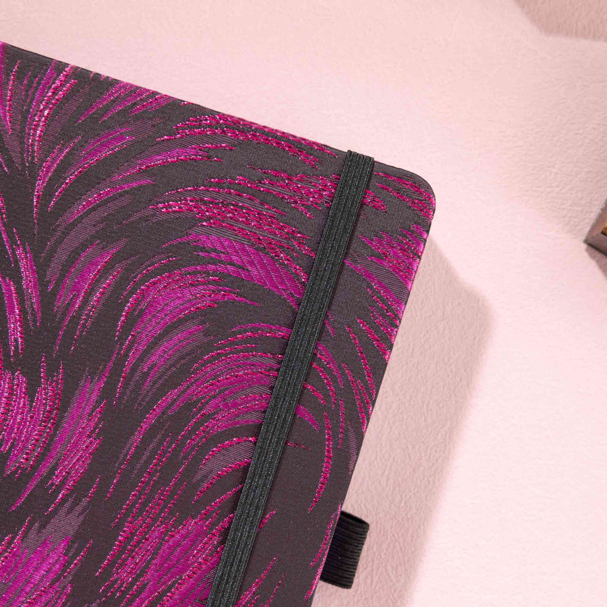 Close-up of the dark purple and black metallic woven fabric cover and matching black elastic strap.