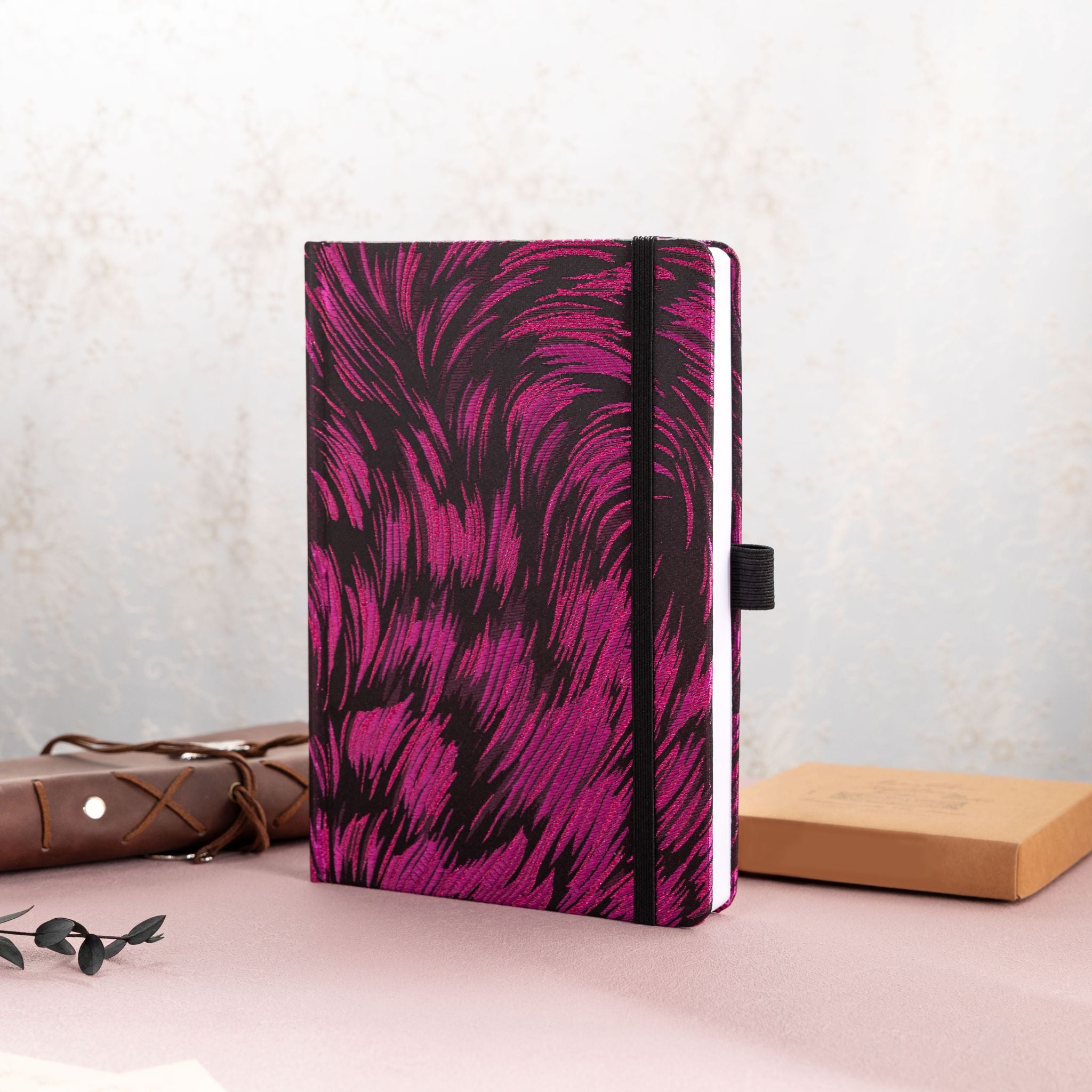 A5 purple and black metallic swirl fabric notebook standing upright on a desk with vintage stationery
