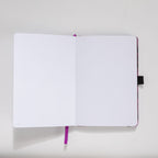 Open A5 journal showing the 160gsm dot grid interior pages and purple ribbon bookmark