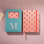 Red scalloped fabric notebook displayed next to its signature light blue window-cut gift box