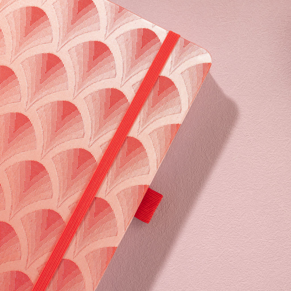 Close-up of the textured red woven scalloped fabric cover and matching red elastic band