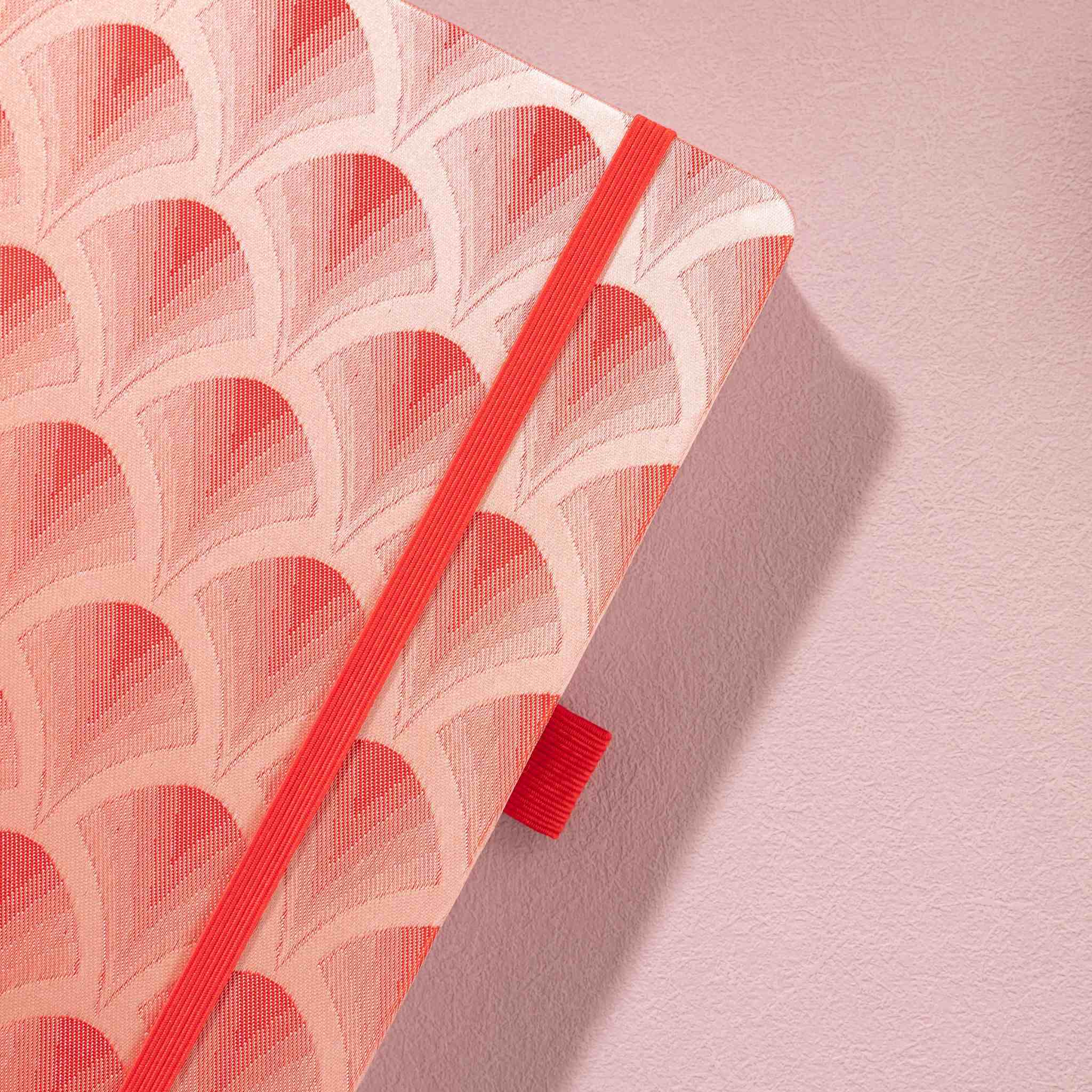 Close-up of the textured red woven scalloped fabric cover and matching red elastic band
