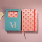 Red scalloped fabric notebook displayed next to its signature light blue window-cut gift box