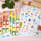 Collection of colorful planner stickers on a pink surface with a flower and branch.