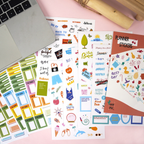Collection of planner stickers on a pink surface with a laptop.