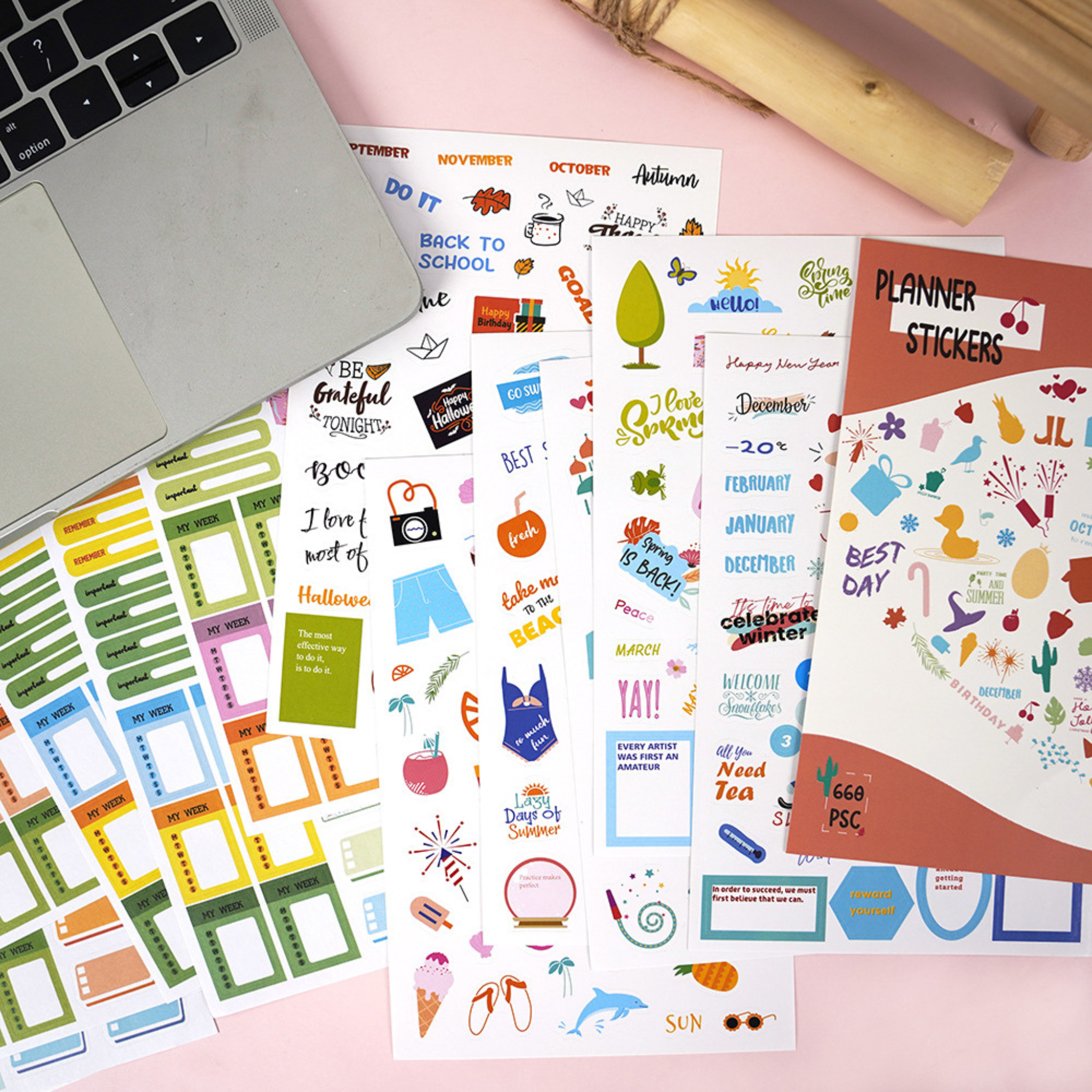 Collection of planner stickers on a pink surface with a laptop.