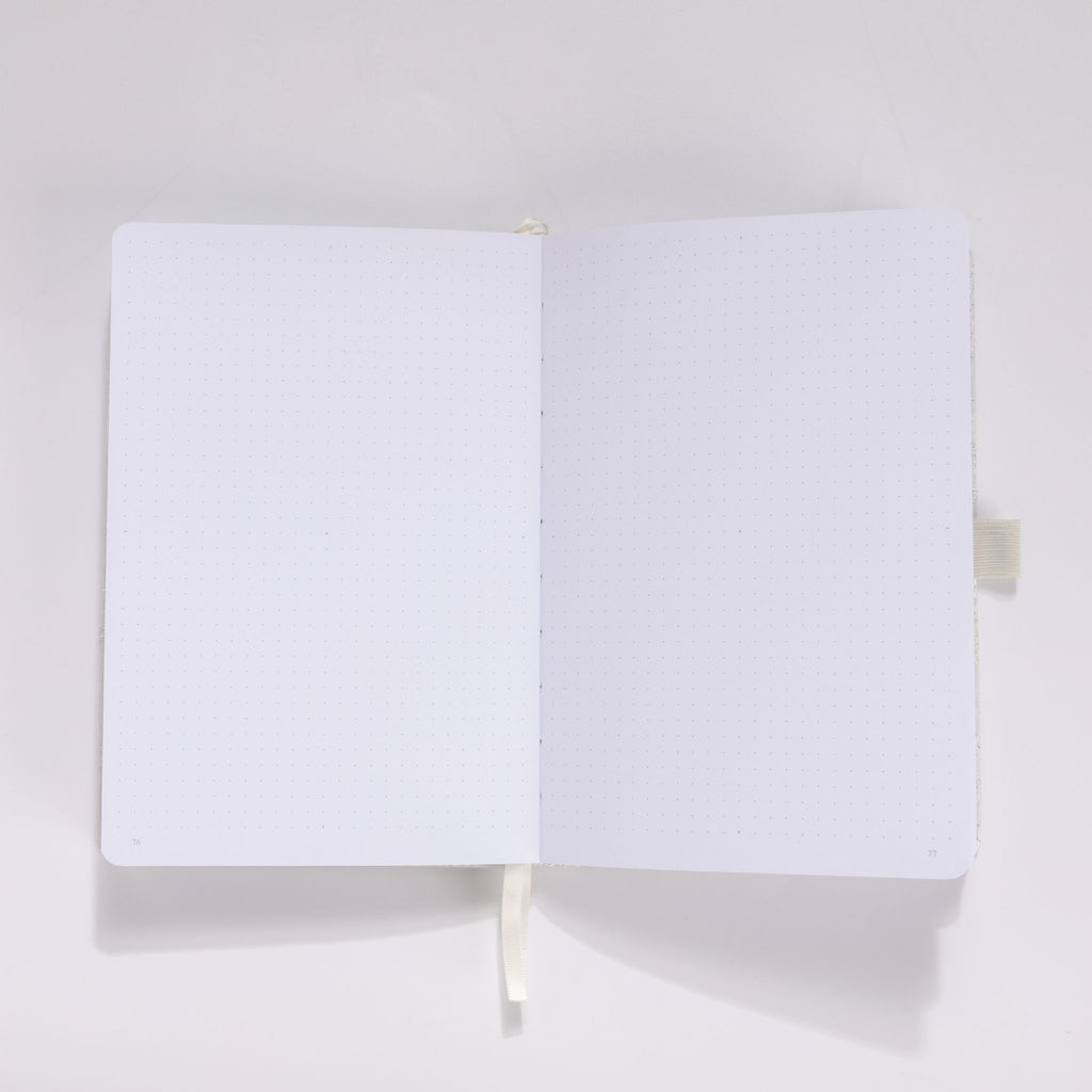 Open A5 journal showing the 160gsm dot grid interior pages with white ribbon bookmark