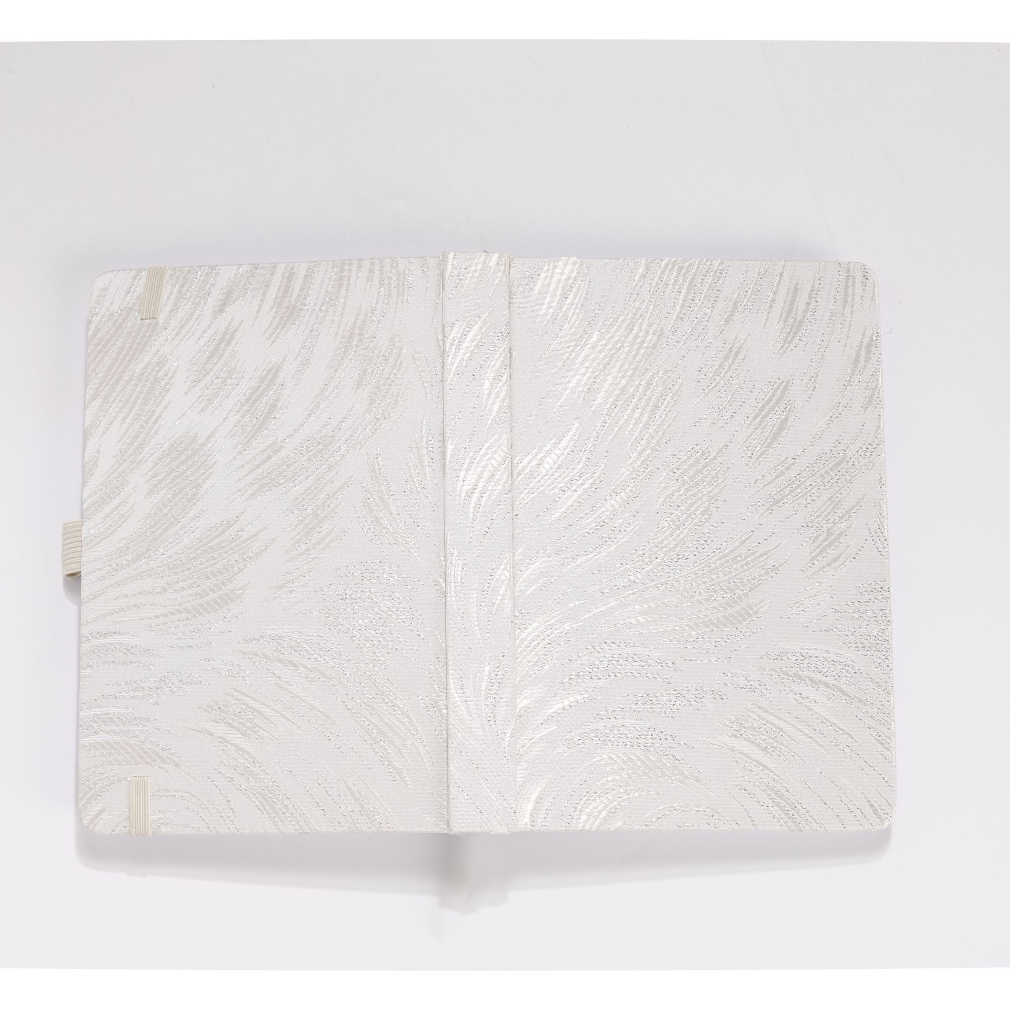 Flat lay of the white and silver embroidered fabric cover opened completely