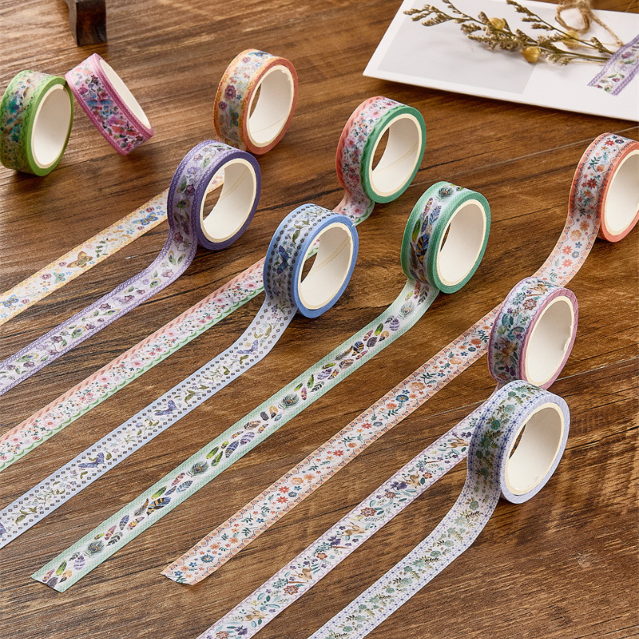 Two stacks of vintage floral and bird washi tape rolls in soft pastel colors, featuring watercolor-style botanical and animal illustrations, standing on a white background.