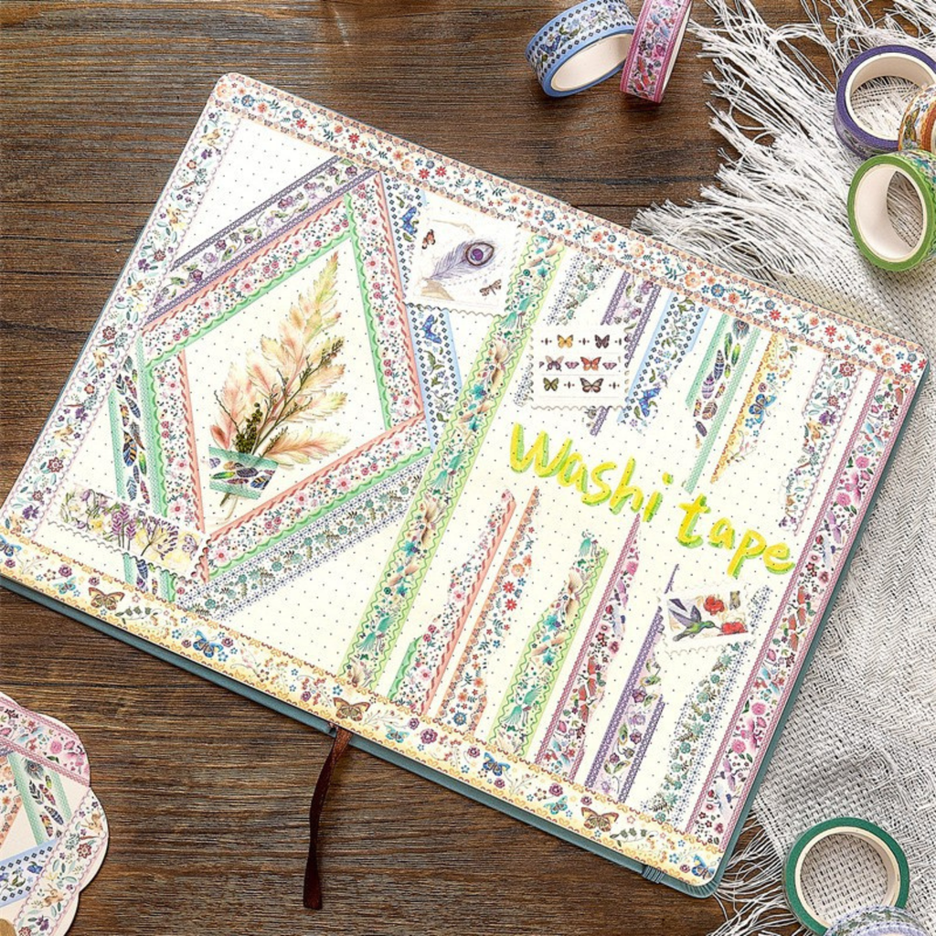 An open bullet journal page decorated with vintage floral and bird washi tapes, featuring floral frames, butterfly accents, and handwritten labels, styled on a wooden desk.