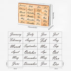 A white storage box containing 24 wooden month stamps featuring both full and abbreviated names in elegant cursive script, with a detailed size guide showing 30×12mm for full spelling and 25×12mm for abbreviated stamps, and the box dimensions marked as 115×76×26mm.