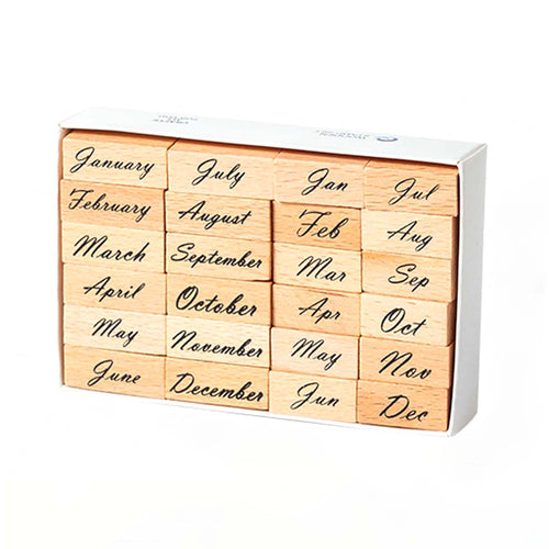 A white storage box containing 24 wooden month stamps arranged in four columns, with full month names on the left and abbreviated forms on the right, displayed on a clean white background.