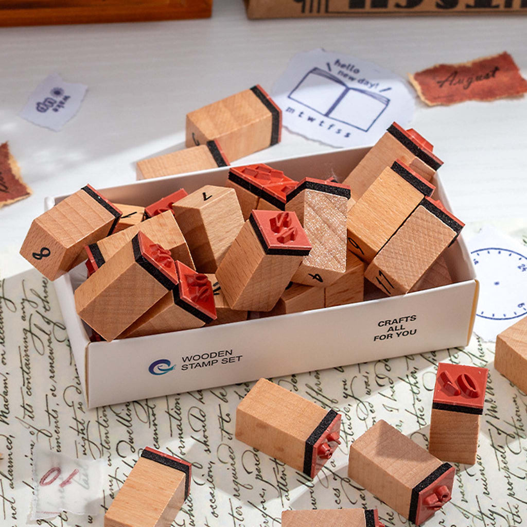 Wooden number stamps scattered on a white desk with vintage handwritten paper, showing the stamps outside their white storage box in a creative journaling setup.