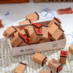 Wooden number stamps scattered on a white desk with vintage handwritten paper, showing the stamps outside their white storage box in a creative journaling setup.