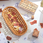 A woven rattan basket filled with stamped paper cutouts and loose wooden number stamps, styled on a desk with vintage script paper for a warm, nostalgic journaling aesthetic.