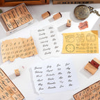 A flat lay of wooden number, weekday, and month stamps arranged on a white desk, featuring stamped paper cutouts in torn edges, vintage script, and a to-do list layout, styled with a brass pocket watch and wooden boxes.