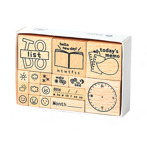 A white storage box containing 17 wooden daily planner stamps, featuring a to-do list frame, weather icons, expression faces, date headers, and a clock face, displayed on a clean white background.